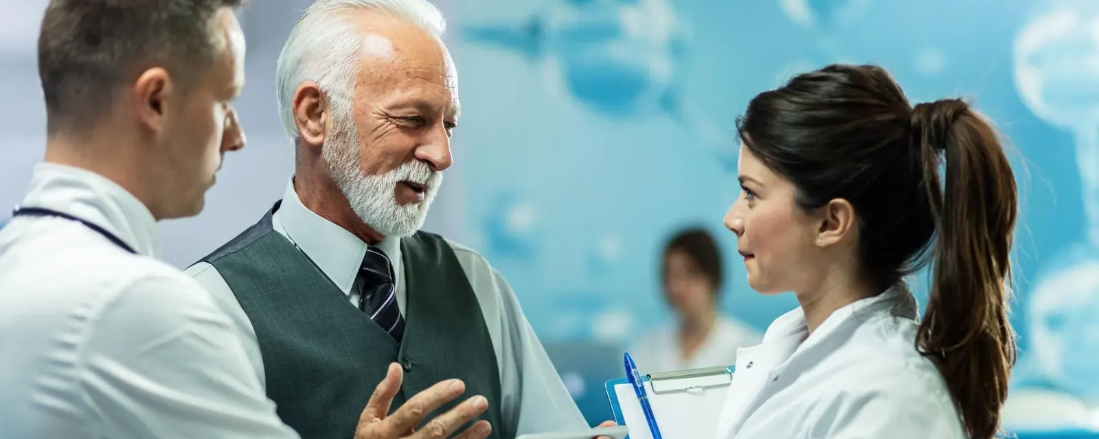 Three clinicians reviewing notes together with a patient in a consulting room