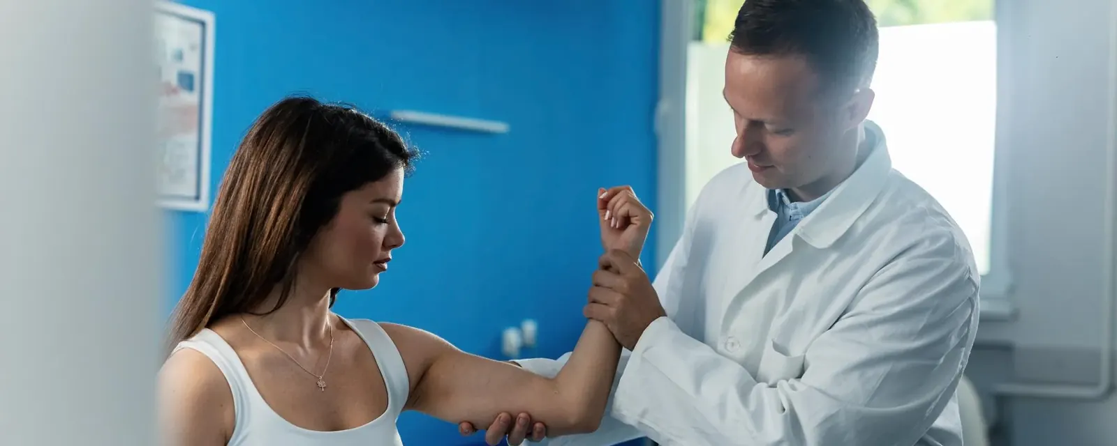 A practitioner examining a patient's elbow and forearm during a musculoskeletal assessment