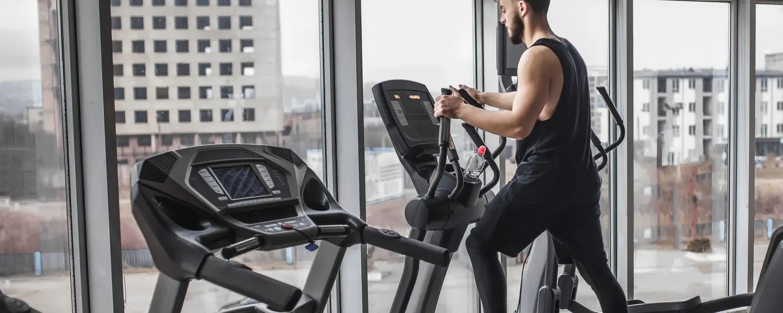 A patient walking on a treadmill beside a window in a rehabilitation gym
